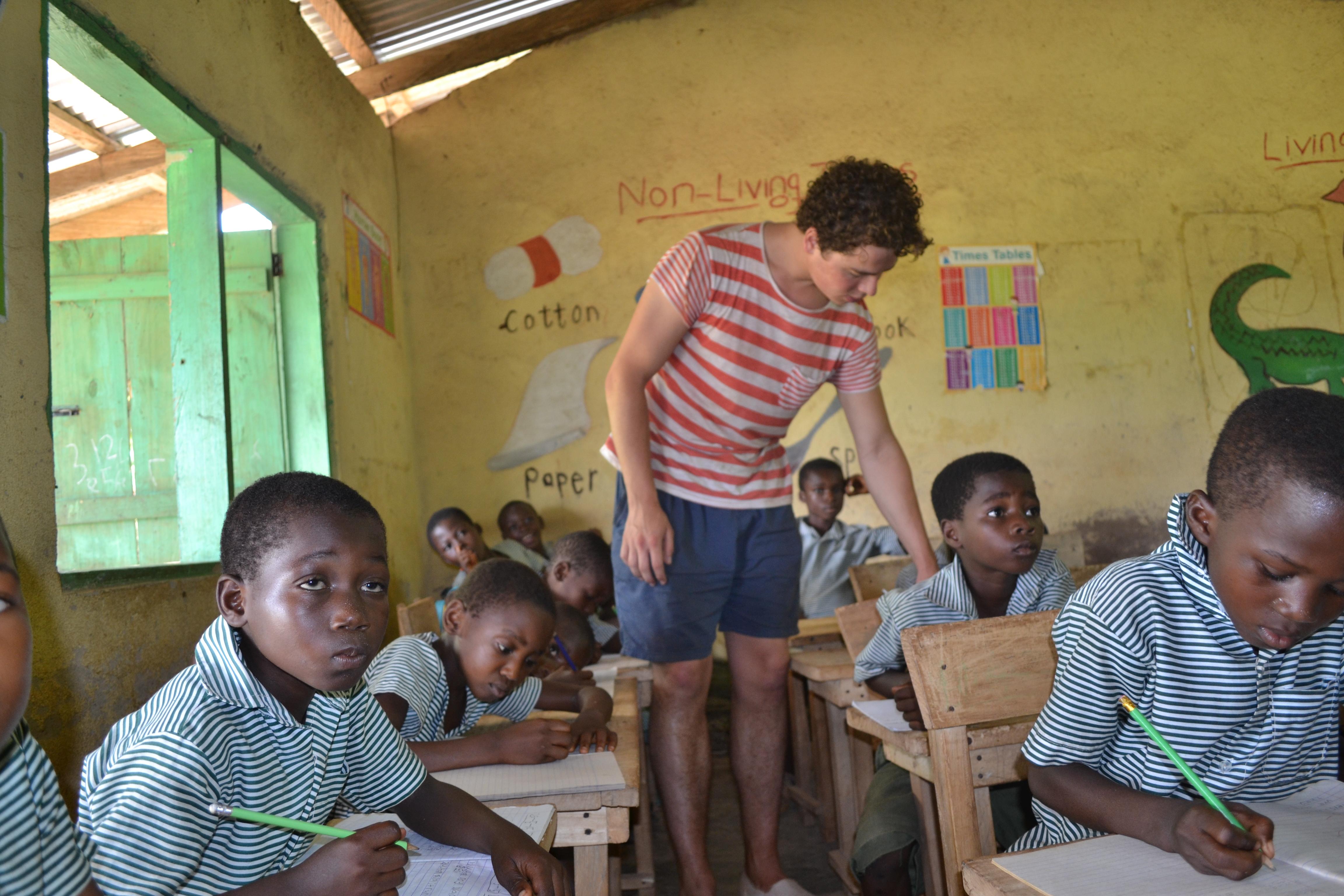 Volunteer teaching in Ghana walks around the classroom and helps his students with their work A Projects Abroad volunteer gains teaching work experience in Ghana by assisting the students who are struggling in class